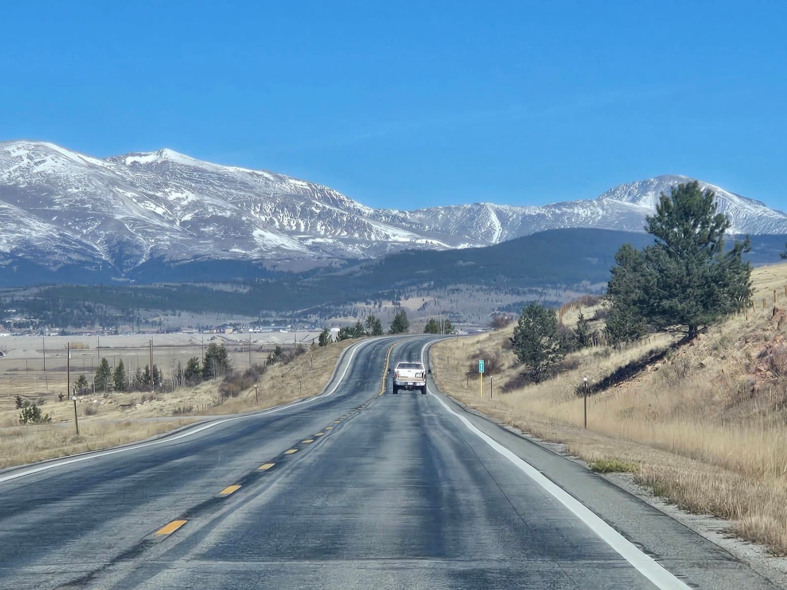 An open highway leading toward snow-capped mountains