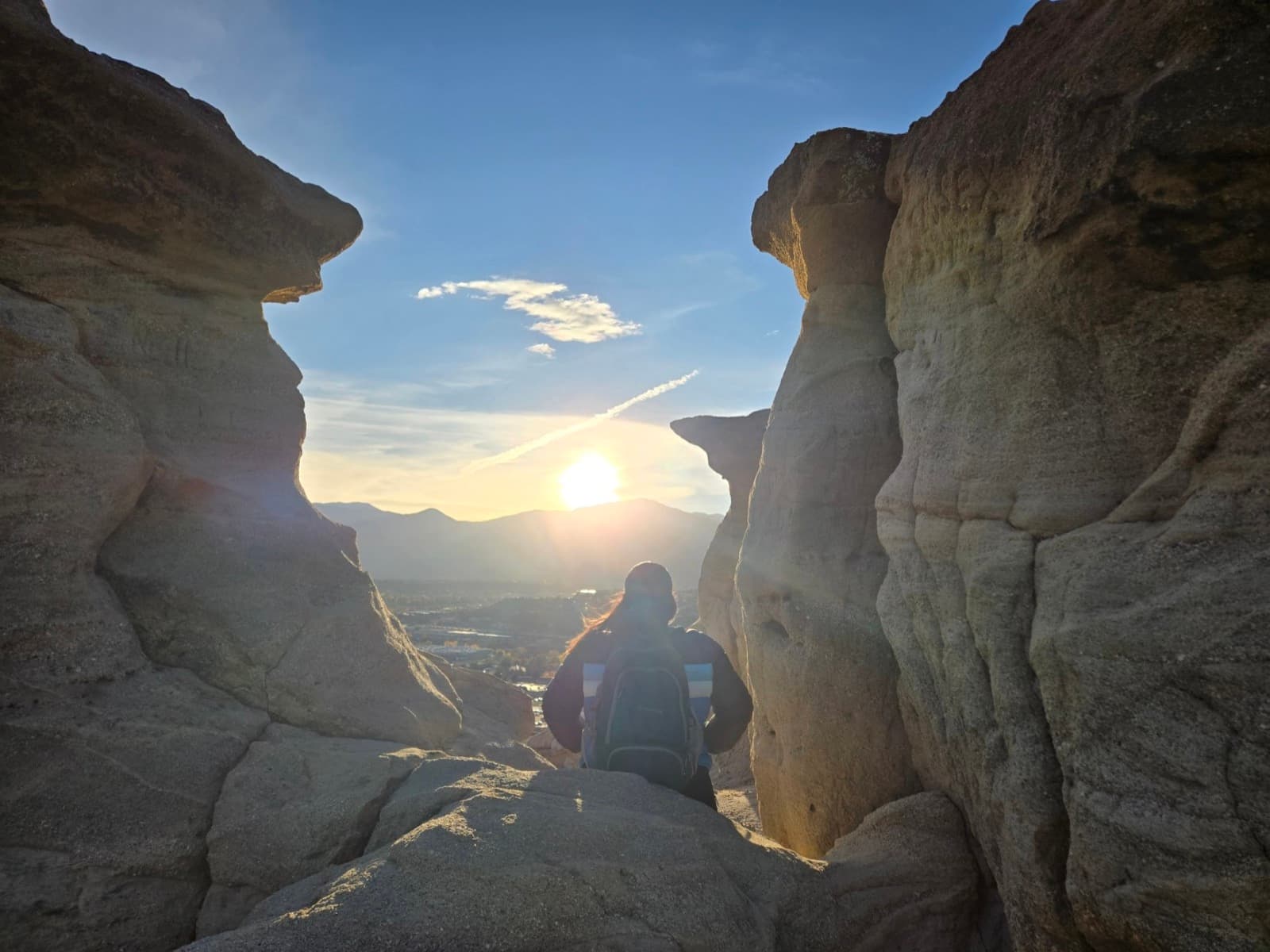 A person sitting between tall rock formations as the sun sets
