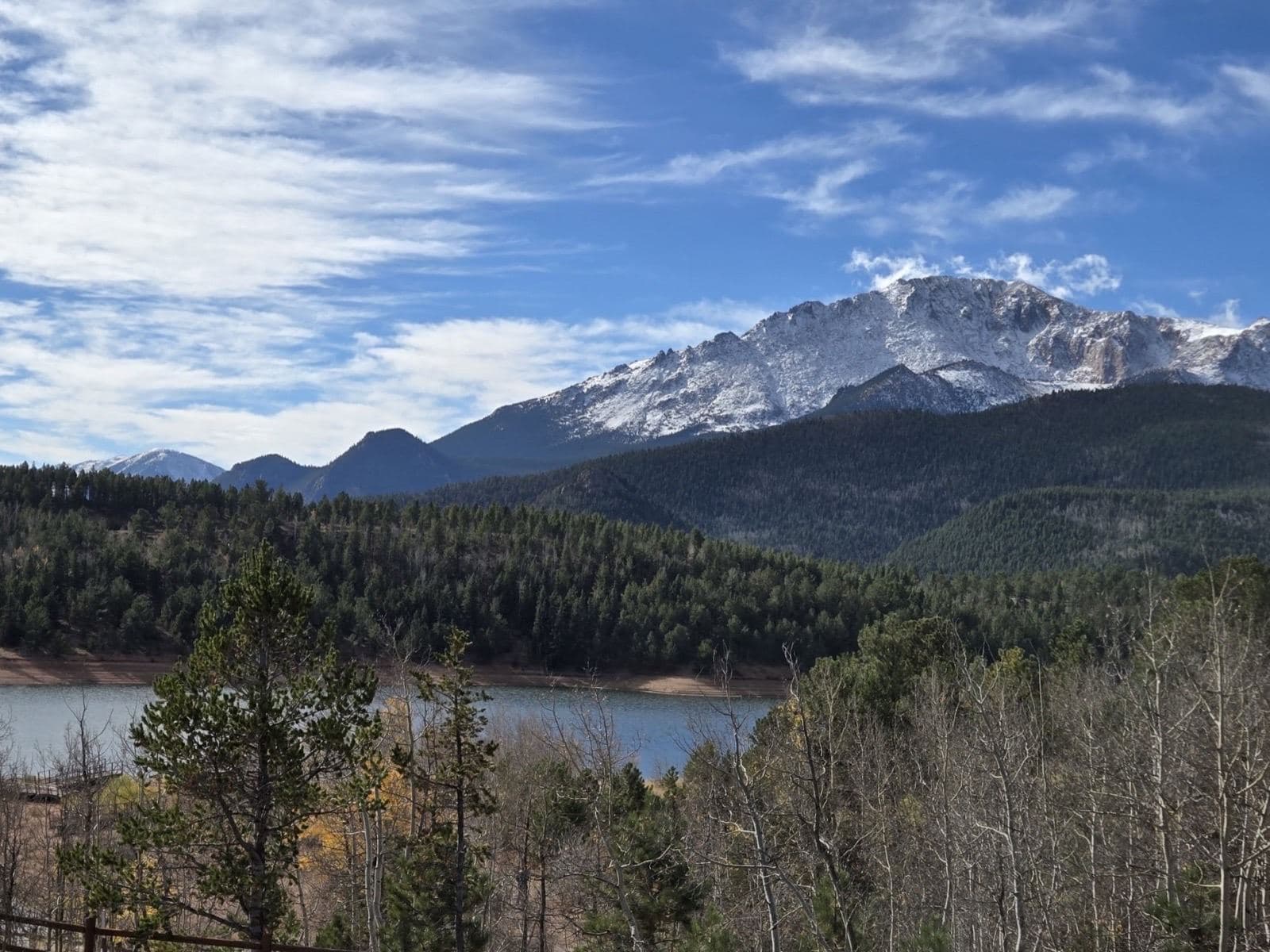 A snow-capped mountain peak above a forested lake
