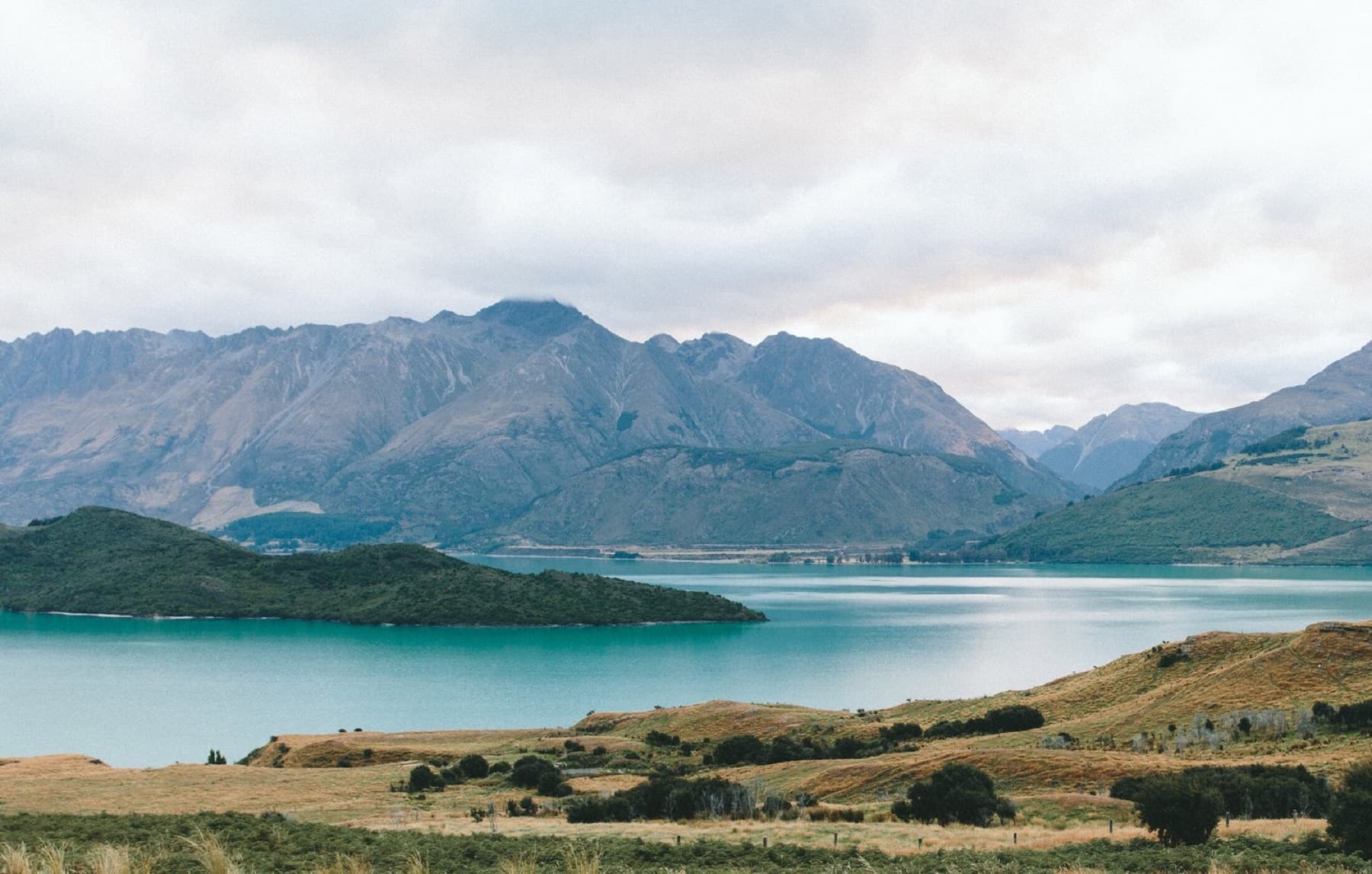 A quiet mountain lake under a soft sky