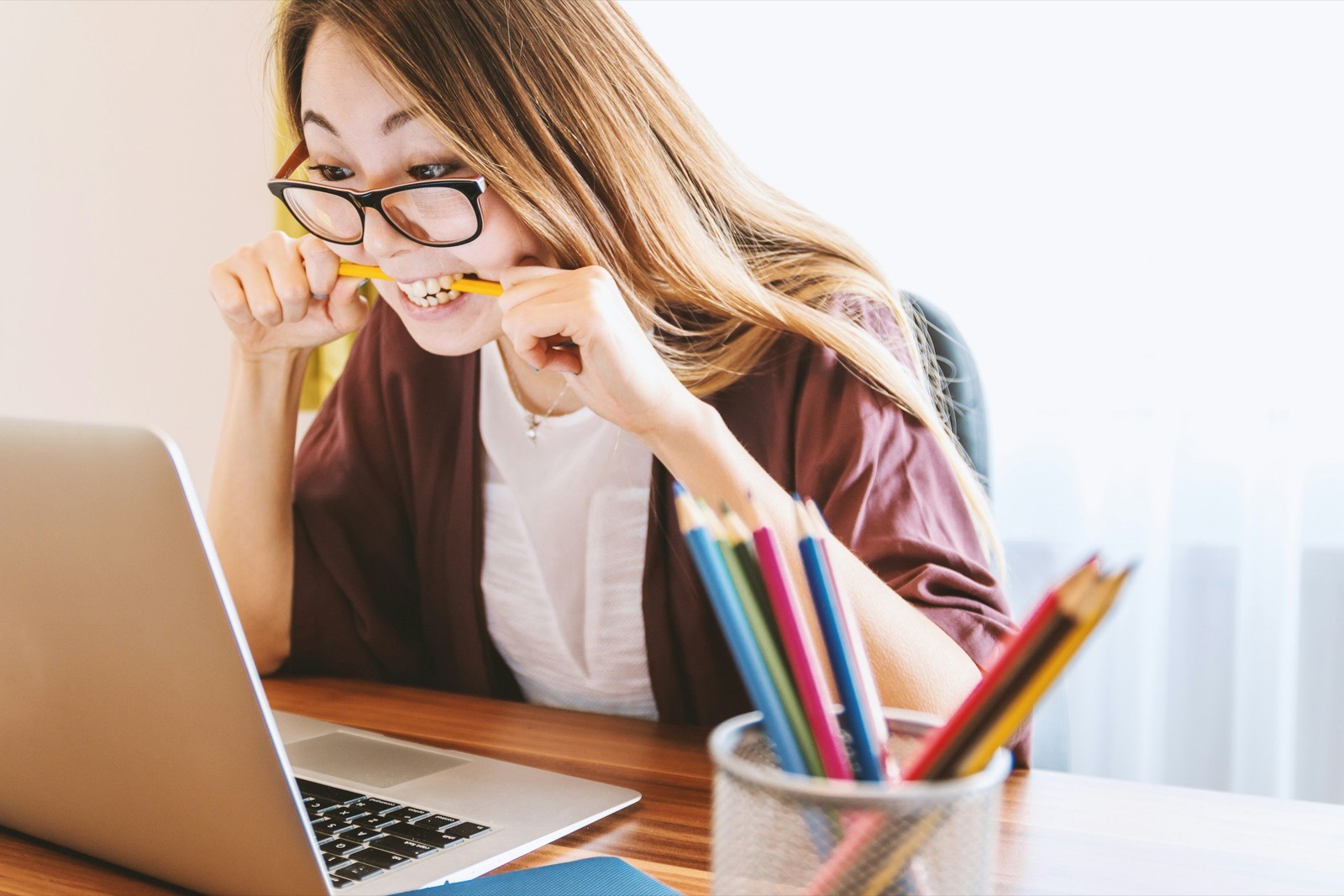 A busy woman at her laptop biting a pencil, short on time for weekly therapy